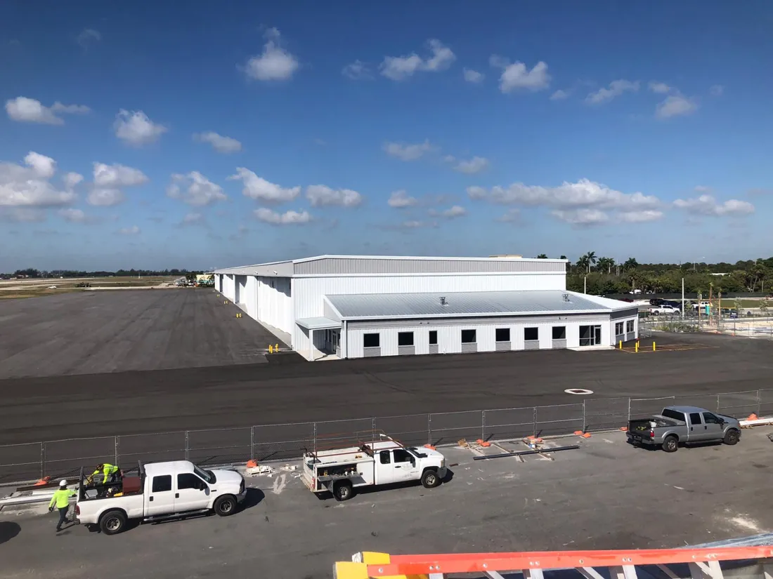 Large commercial facility with metal roof, Icon Roofing crew trucks on site